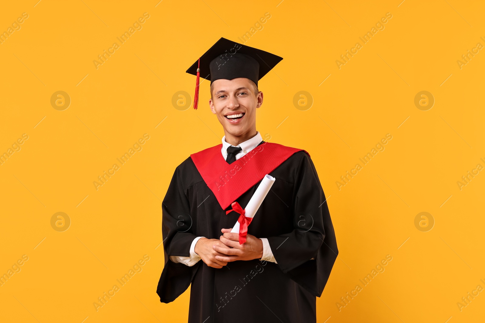 Photo of Happy student with diploma after graduation on orange background