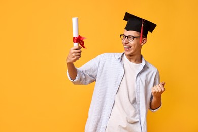 Photo of Happy student with diploma after graduation on orange background. Space for text