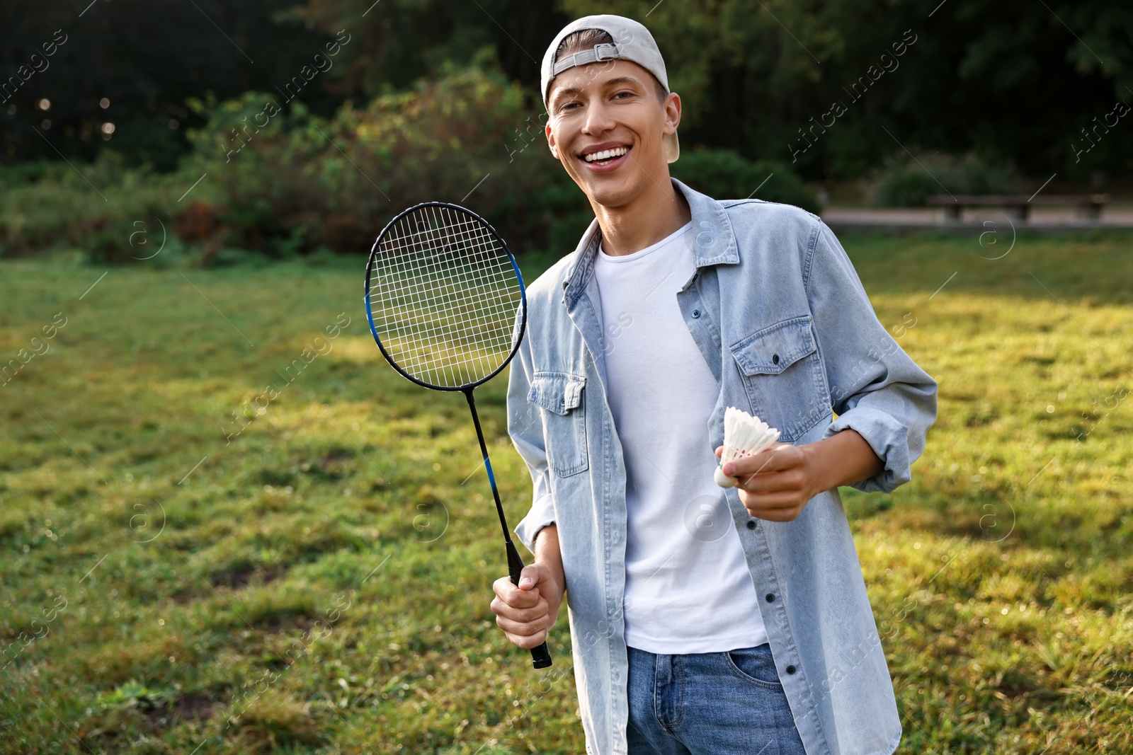 Photo of Happy young man with badminton racket and shuttlecock in park