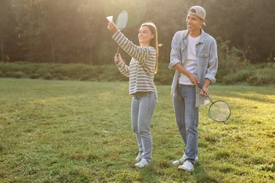 Photo of Young woman and man playing badminton in park on sunny day