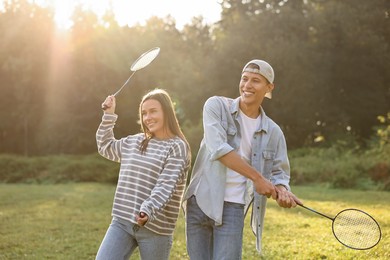 Photo of Young woman and man playing badminton in park on sunny day