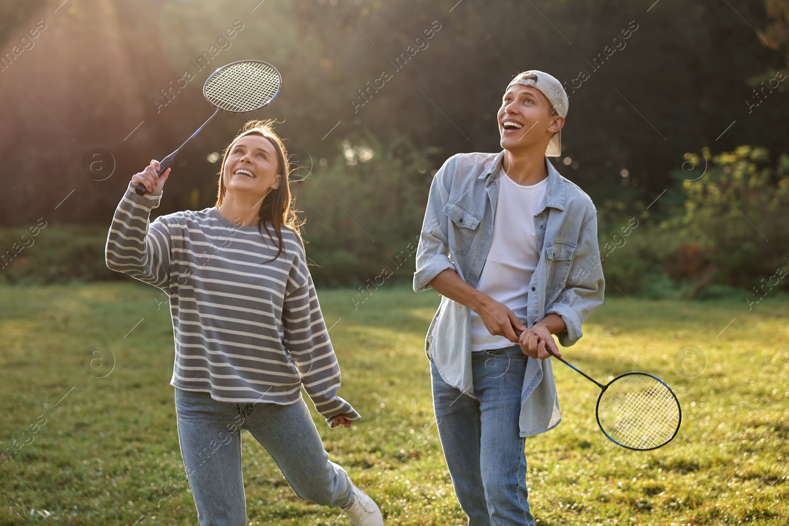 Photo of Young woman and man playing badminton in park on sunny day