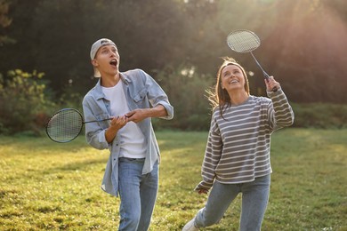 Photo of Young woman and man playing badminton in park on sunny day