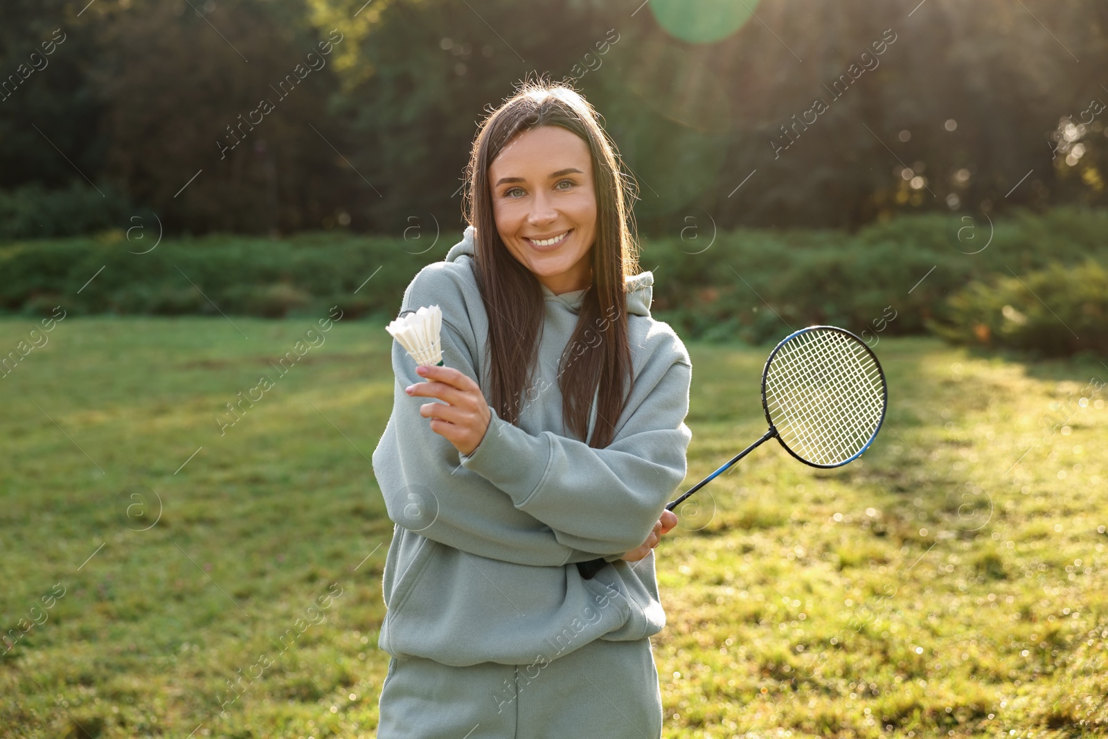 Photo of Happy young woman with badminton racket and shuttlecock in park on sunny day