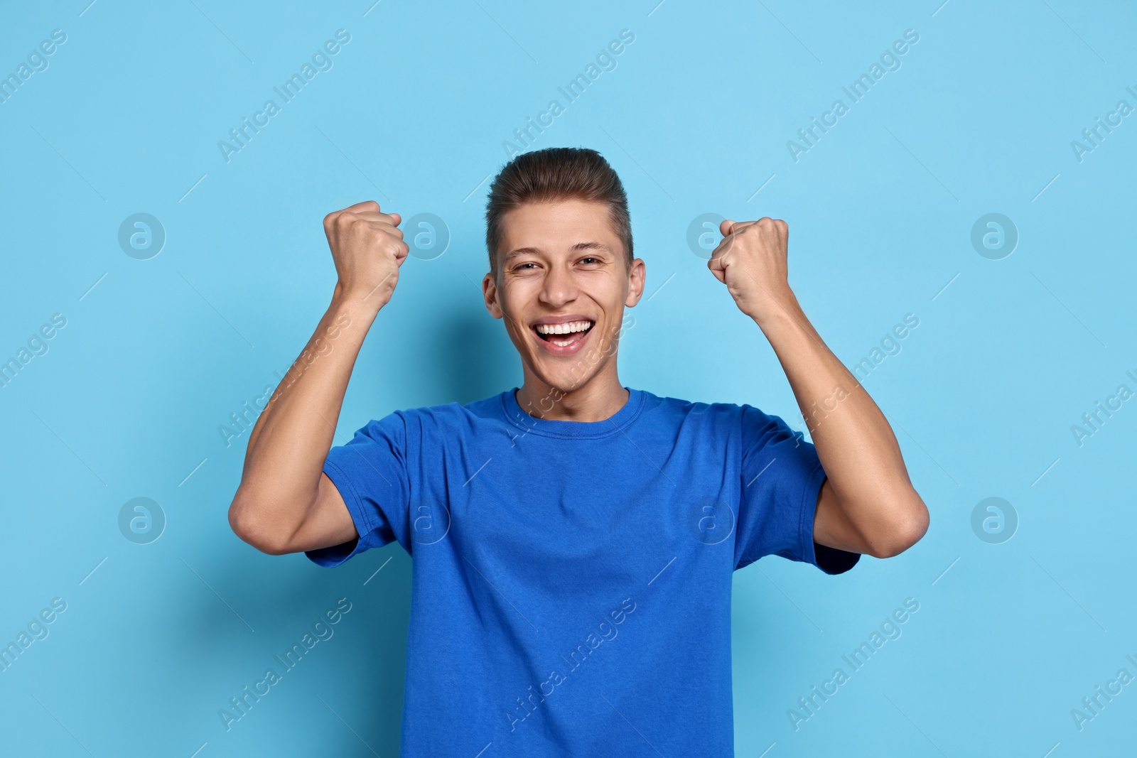 Photo of Student feeling happy about his good exam result on light blue background