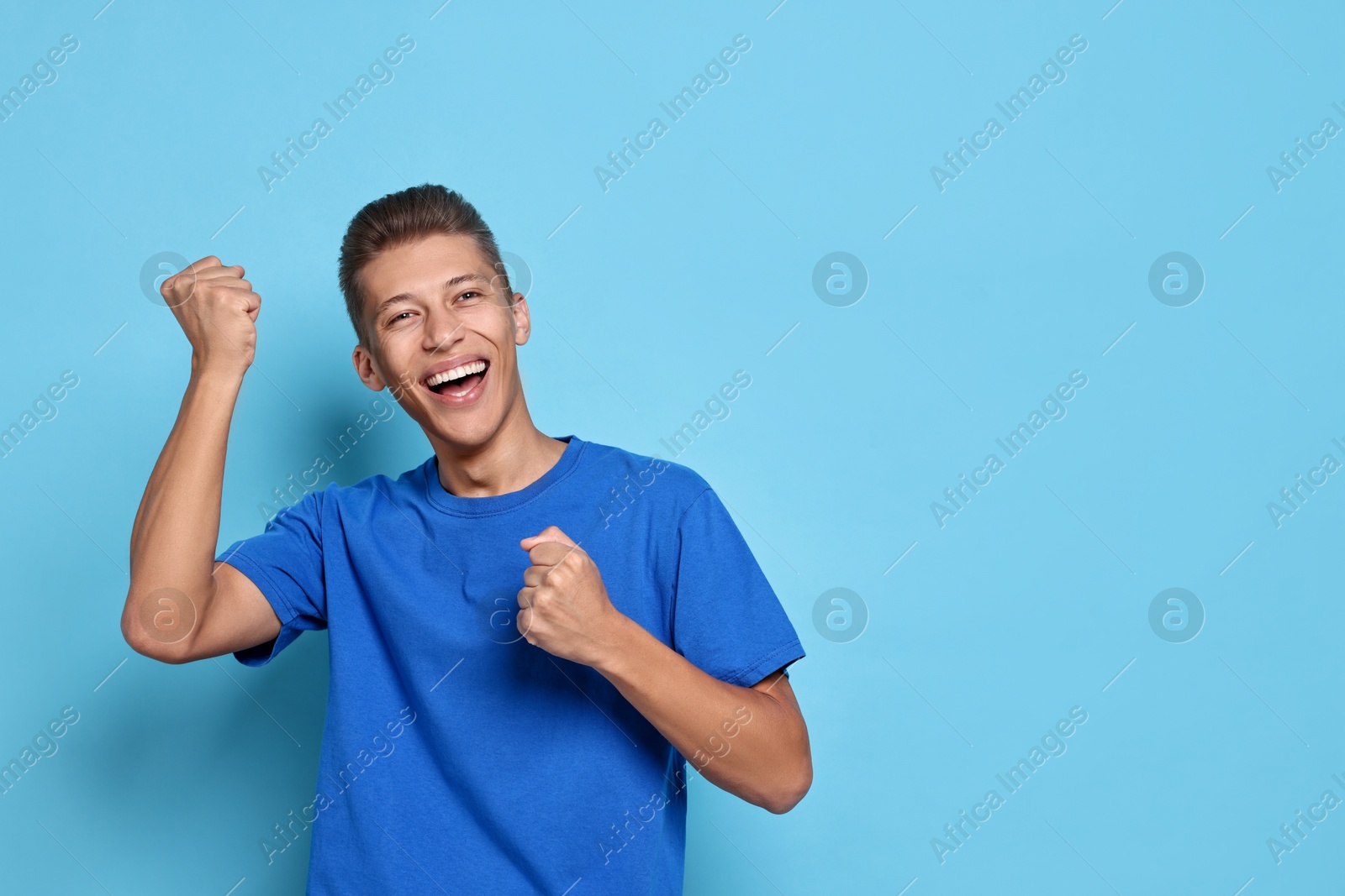 Photo of Student feeling happy about his good exam result on light blue background. Space for text