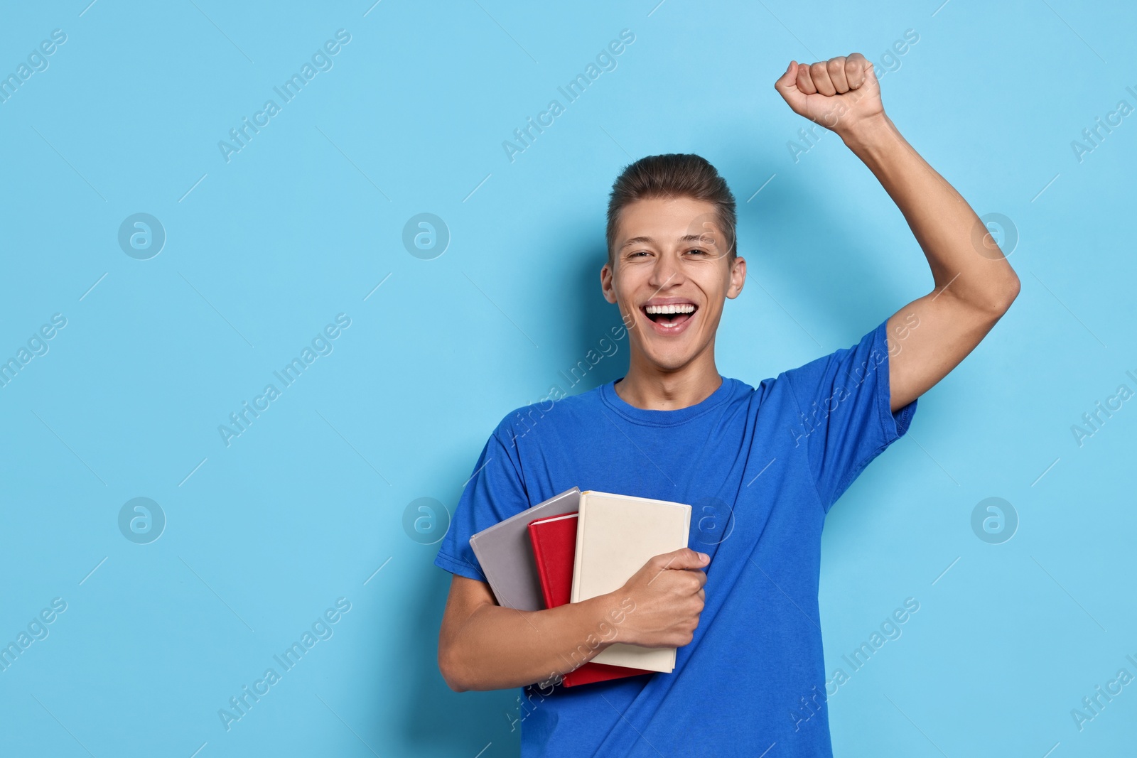 Photo of Happy student with stack of books on light blue background