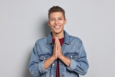 Photo of Student with clasped hands happy about his good exam result on grey background