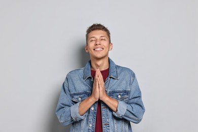 Photo of Student with clasped hands happy about his good exam result on grey background