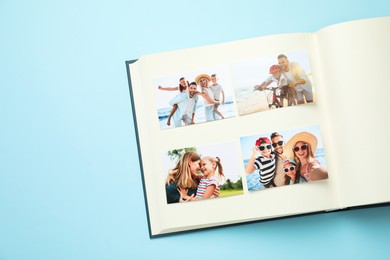 Photo of Open photo album with different photos on light blue background, top view. Space for text