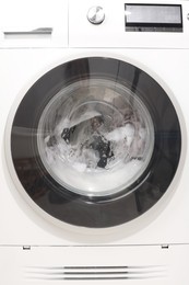 Photo of Washing machine with clothes as background, closeup