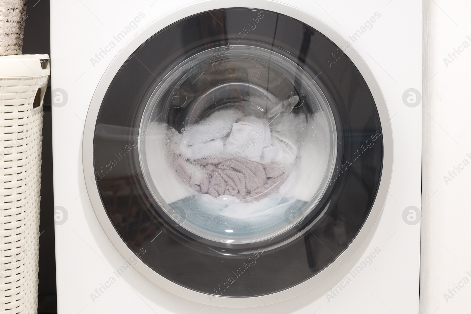 Photo of Washing machine with clothes as background, closeup