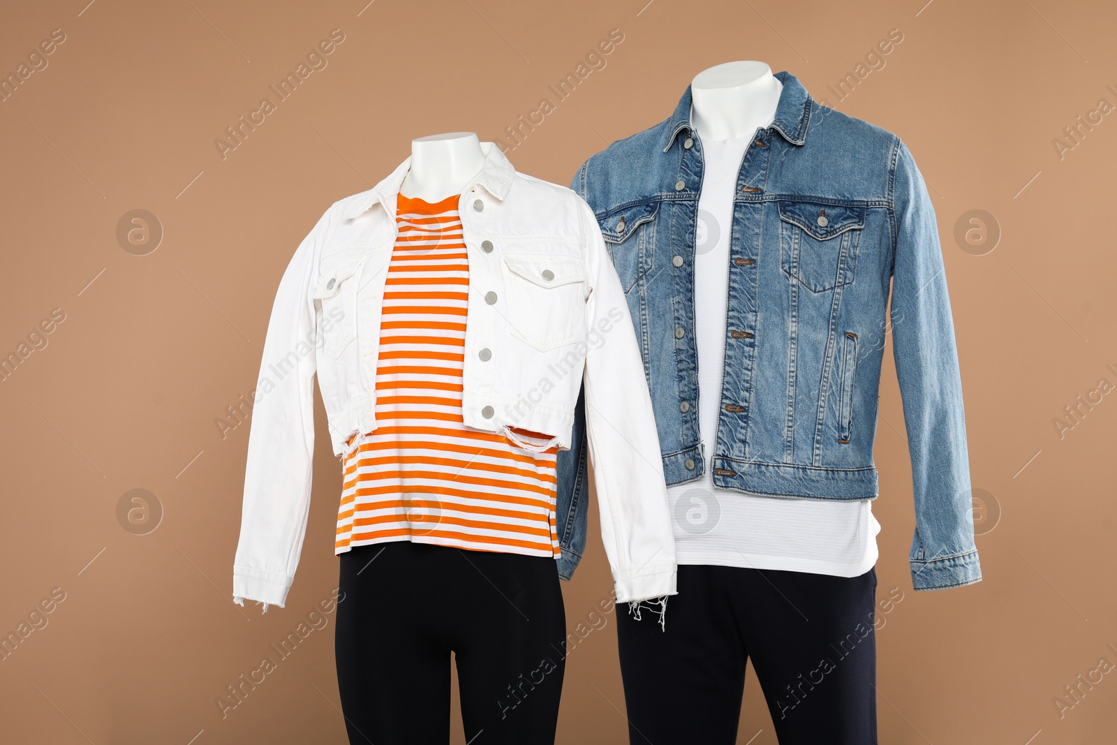 Photo of Female and male mannequins with stylish outfits on light brown background