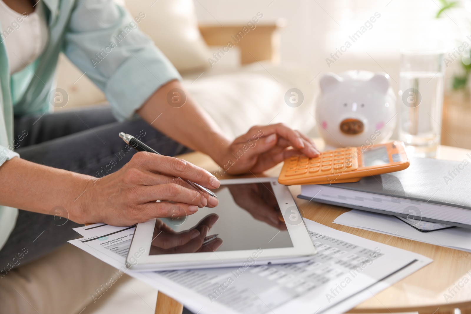 Photo of Budget planning. Woman using calculator and tablet at table indoors, closeup