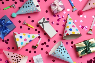 Photo of Shiny confetti and party decor on pink background, flat lay