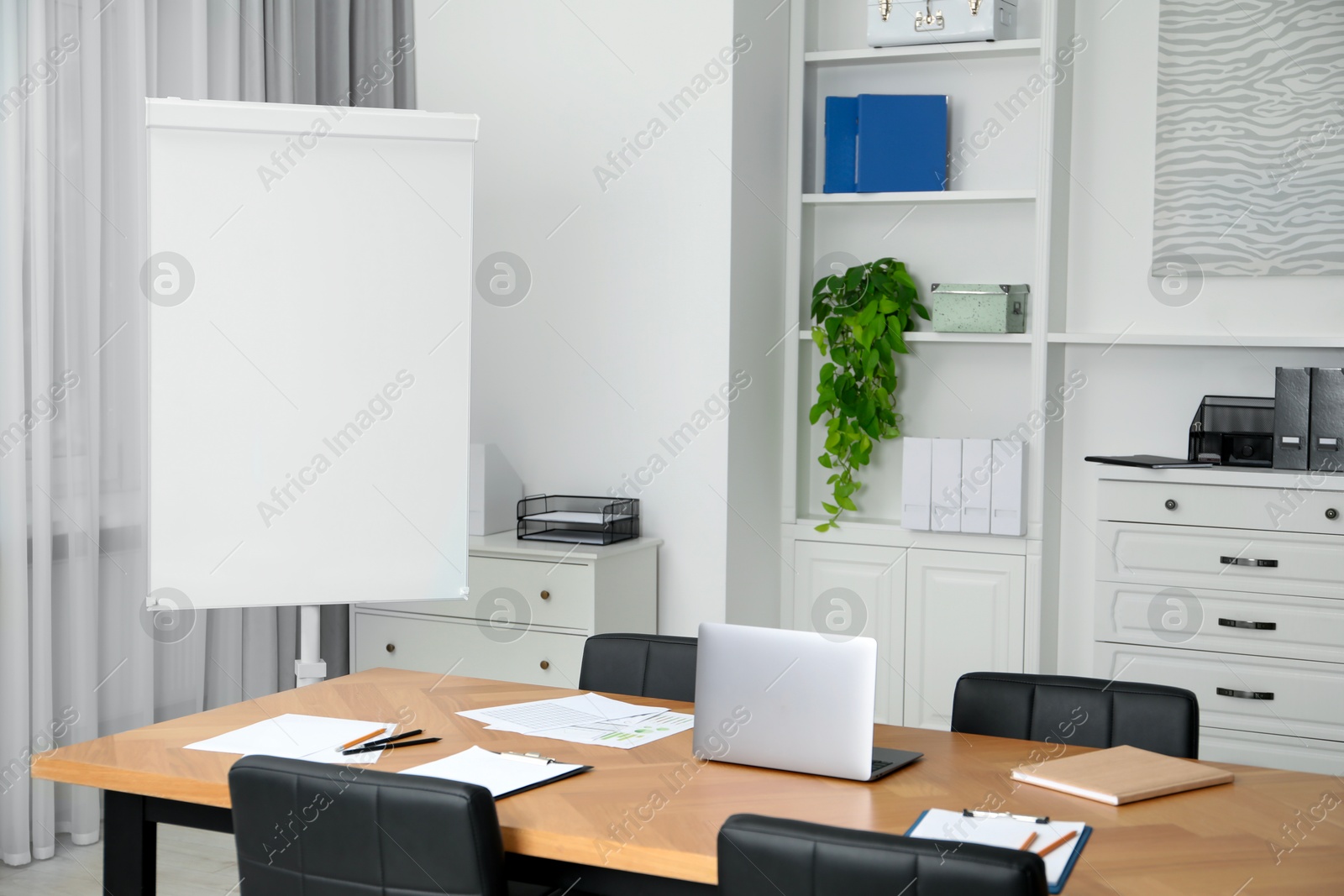 Photo of Flip chart, wooden table and chairs in conference room. Mockup for design