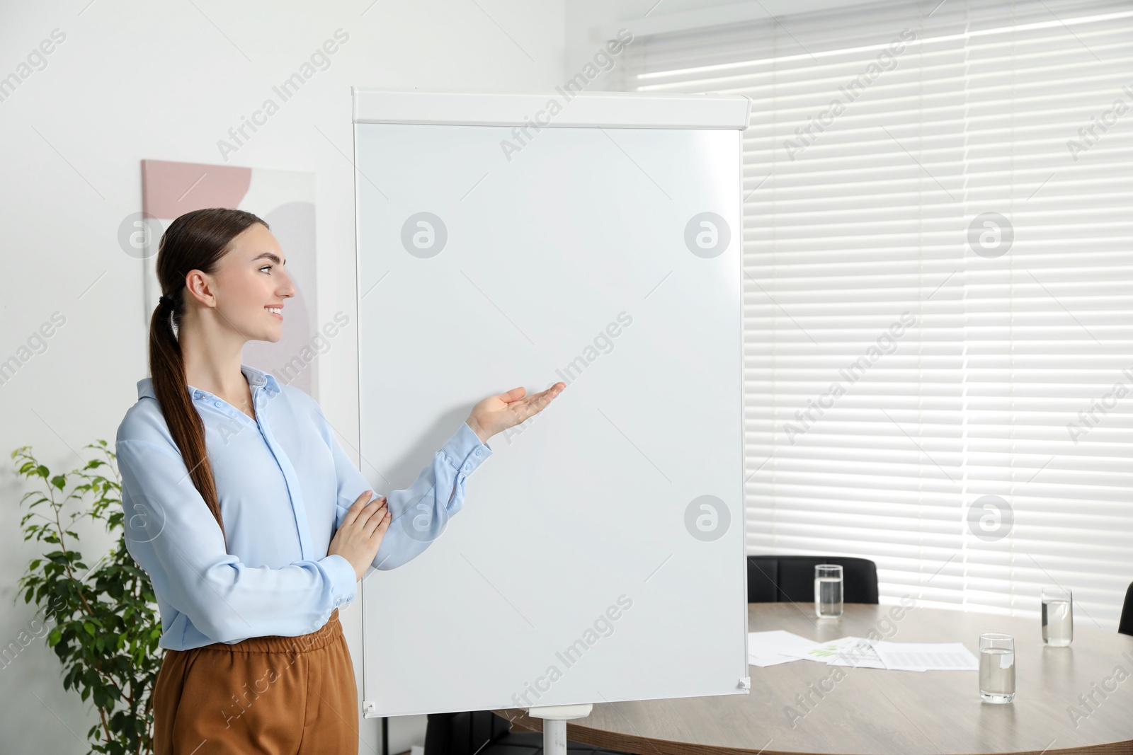 Photo of Happy woman near flip chart in office. Mockup for design