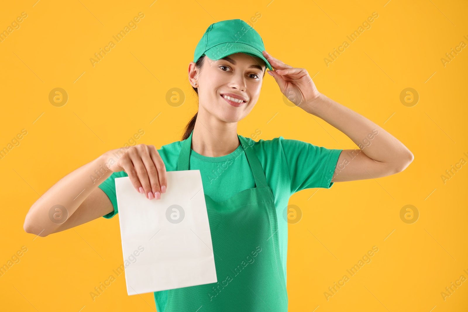 Photo of Fast-food worker with paper bag on orange background