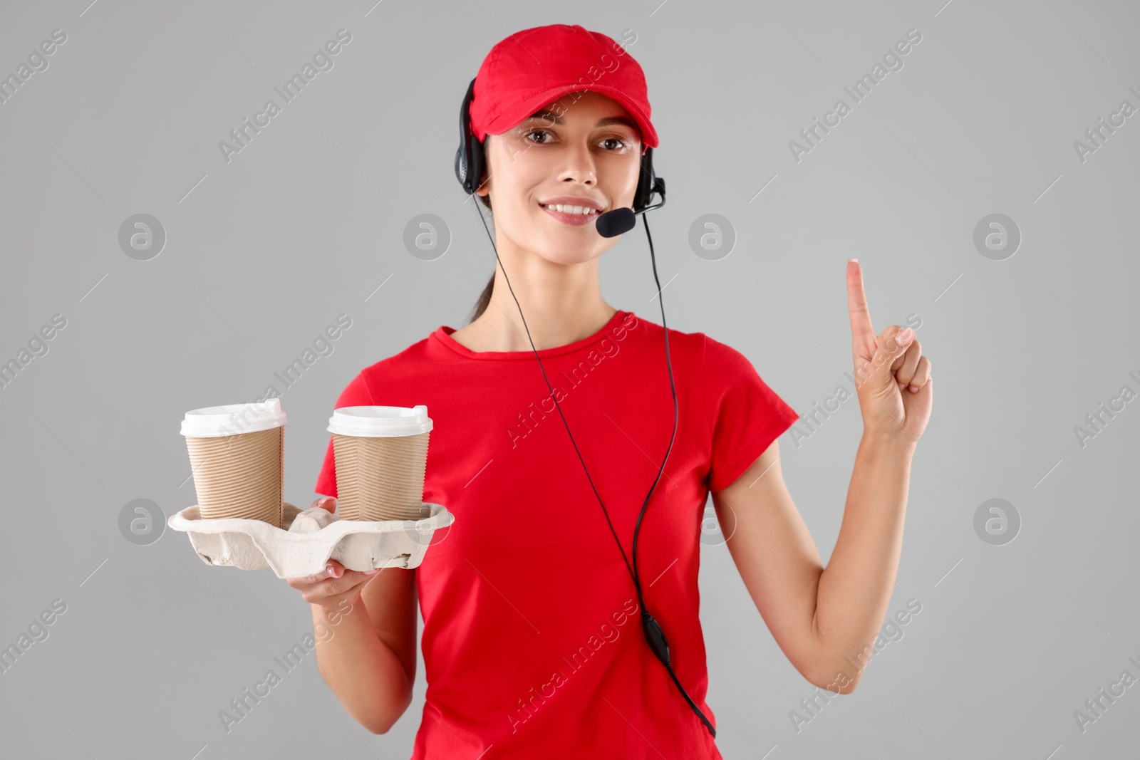 Photo of Fast-food worker with paper cups on gray background