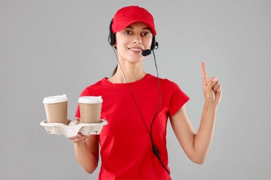 Photo of Fast-food worker with paper cups on gray background