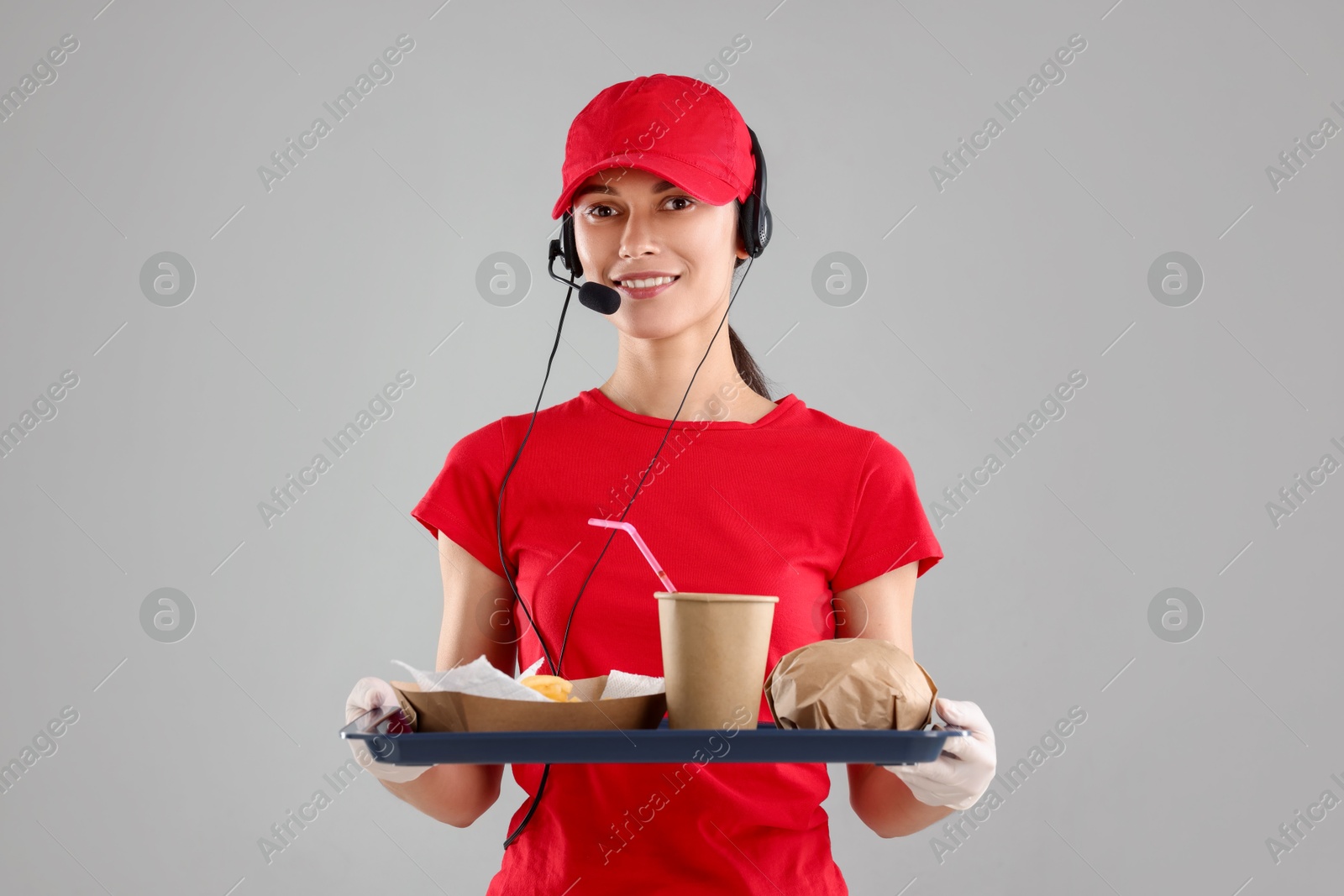 Photo of Fast-food worker holding tray with order on gray background,