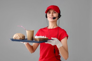 Photo of Fast-food worker holding tray with order on gray background,