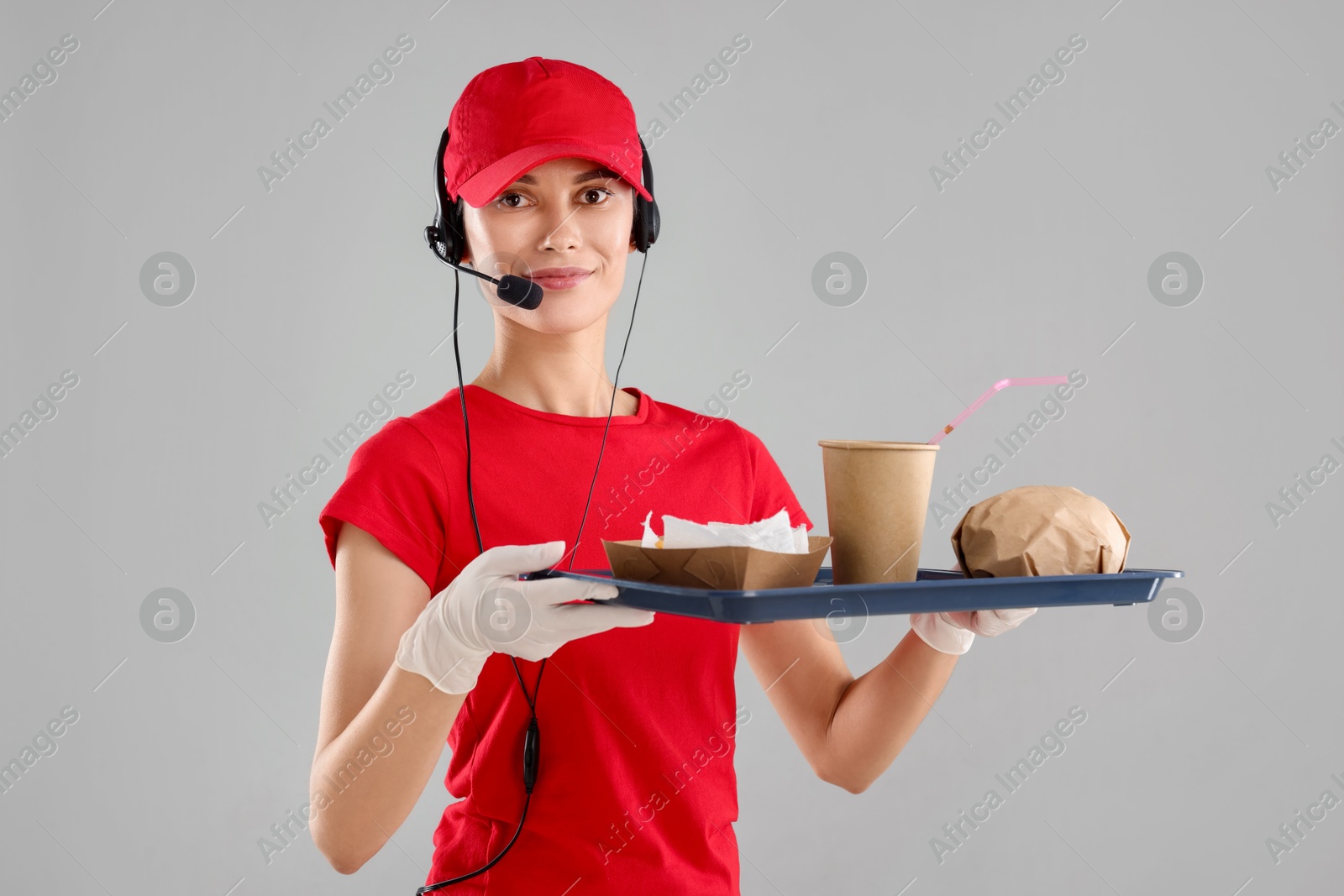 Photo of Fast-food worker holding tray with order on gray background,