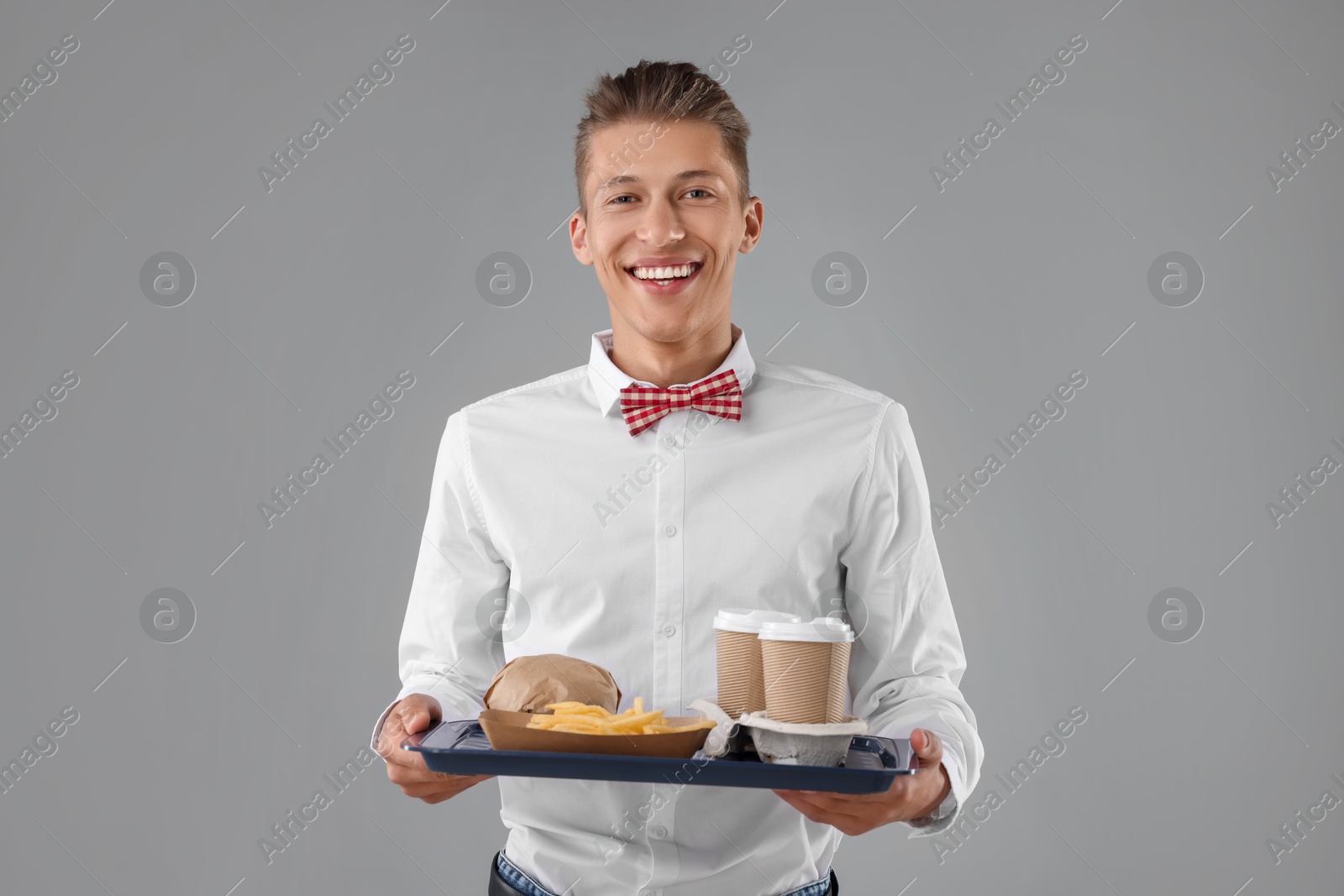 Photo of Fast-food worker holding tray with order on gray background