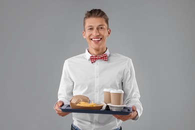 Fast-food worker holding tray with order on gray background