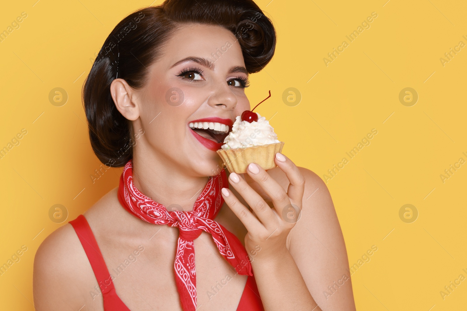 Photo of Pin-up woman eating cupcake on orange background