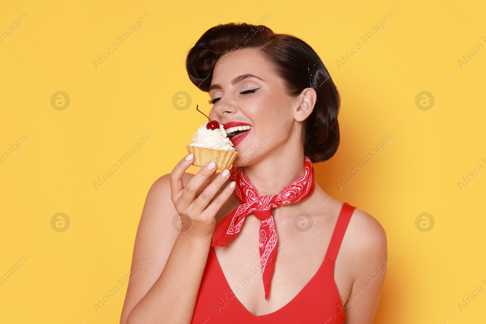 Photo of Pin-up woman eating cupcake on orange background