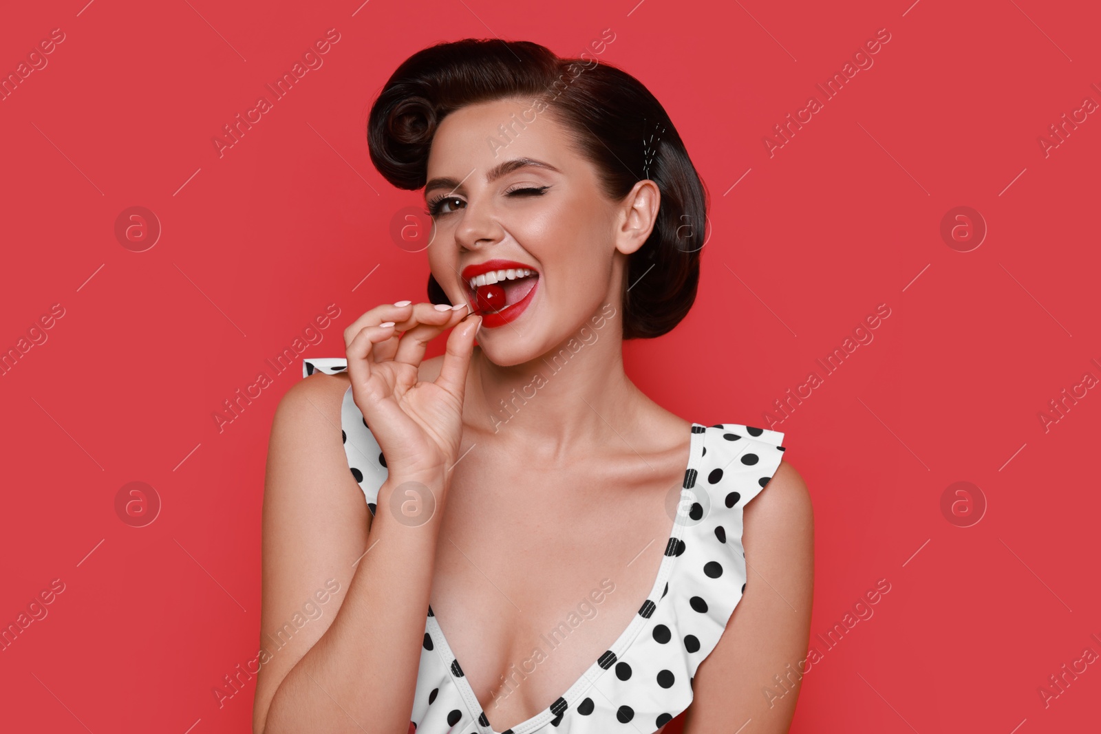 Photo of Pin-up woman in bikini eating cherry on red background