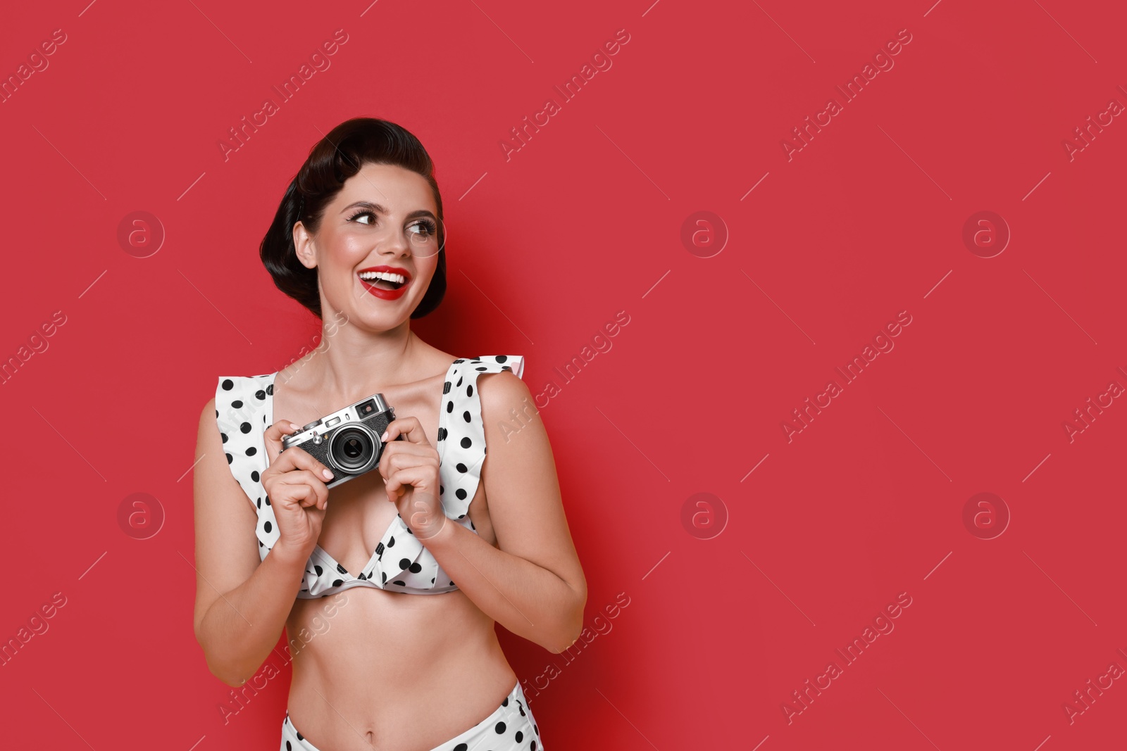 Photo of Pin-up woman in bikini with camera on red background, space for text