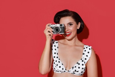 Pin-up woman in bikini with camera on red background