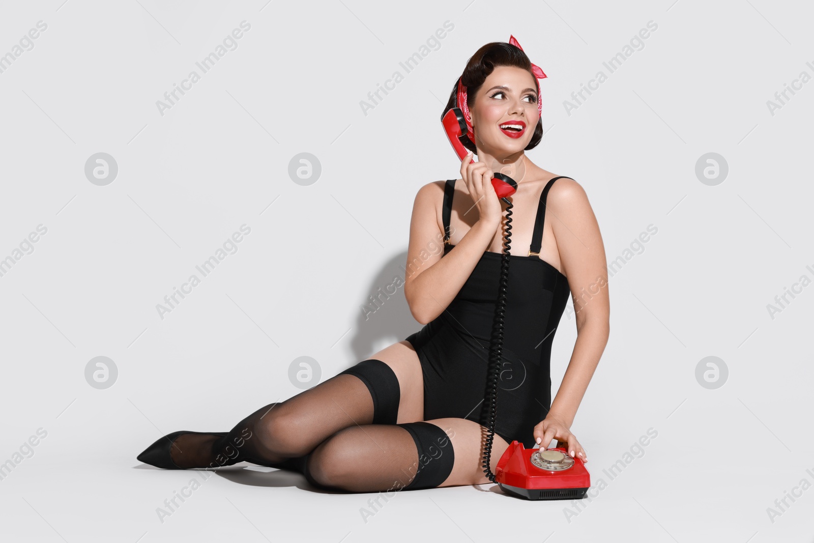 Photo of Pin-up woman with telephone on light background