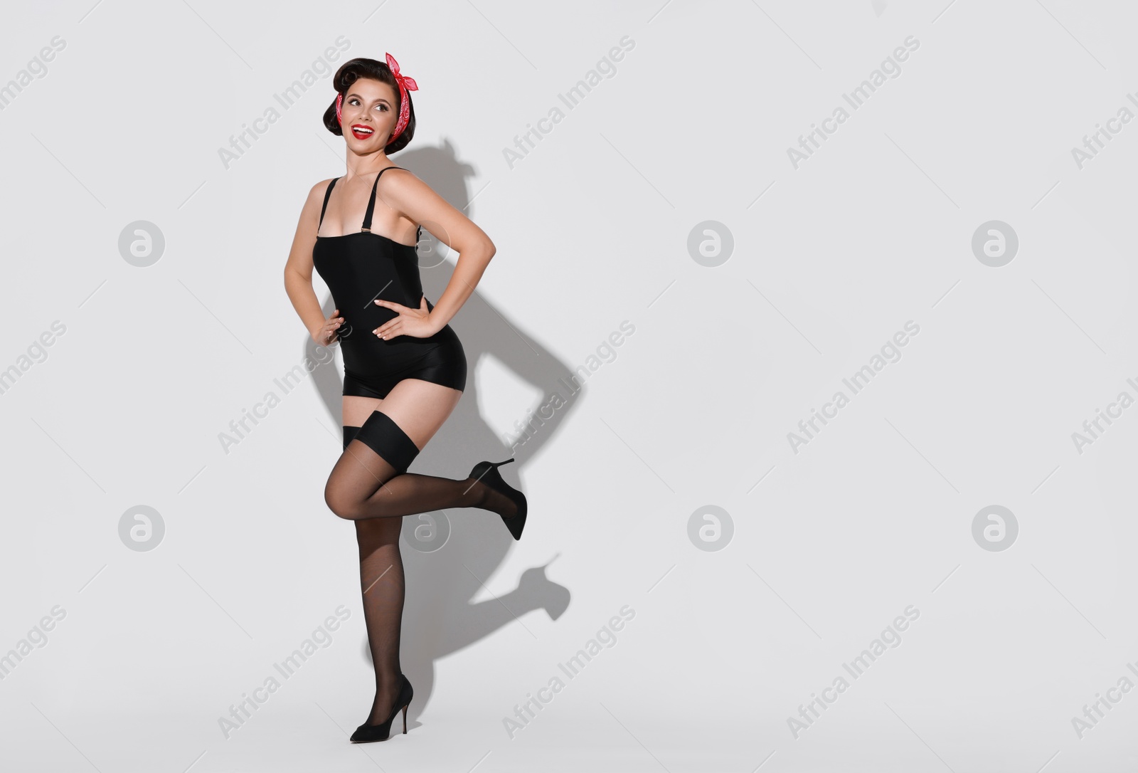 Photo of Pin-up woman in black underwear on light background