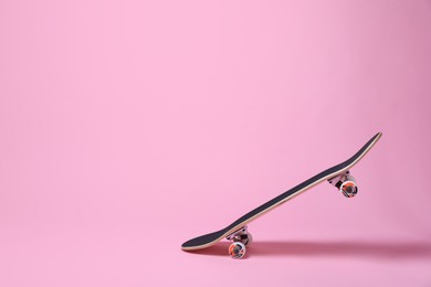 Photo of One skateboard on pink background, space for text. Sports equipment