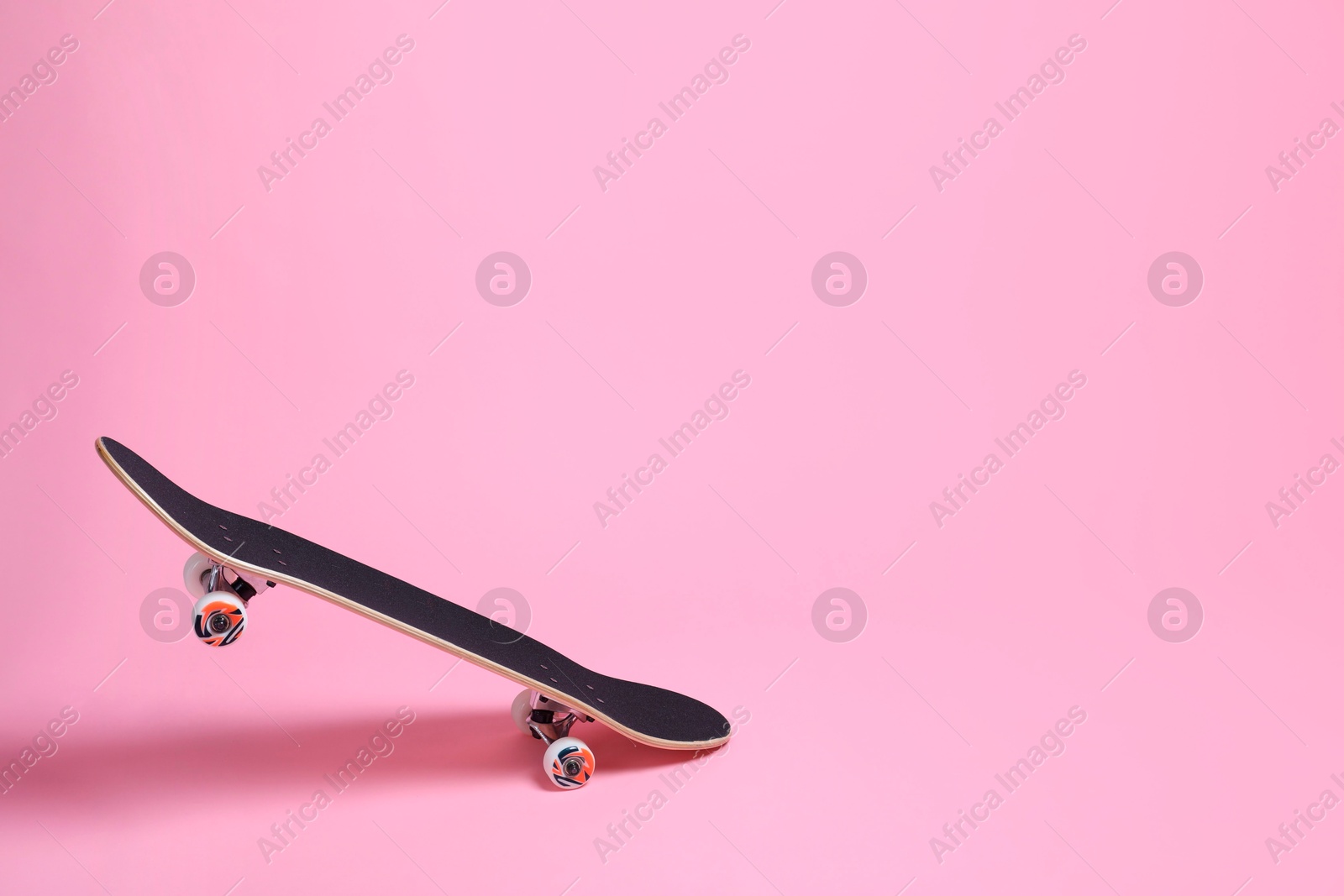 Photo of One skateboard on pink background, space for text. Sports equipment