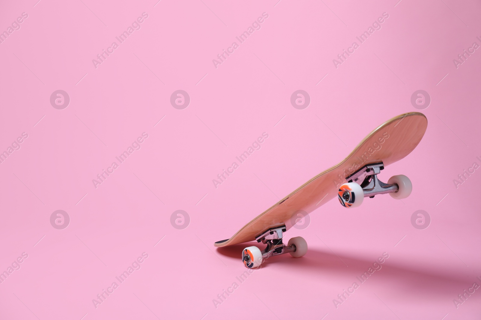 Photo of One skateboard on pink background, space for text. Sports equipment