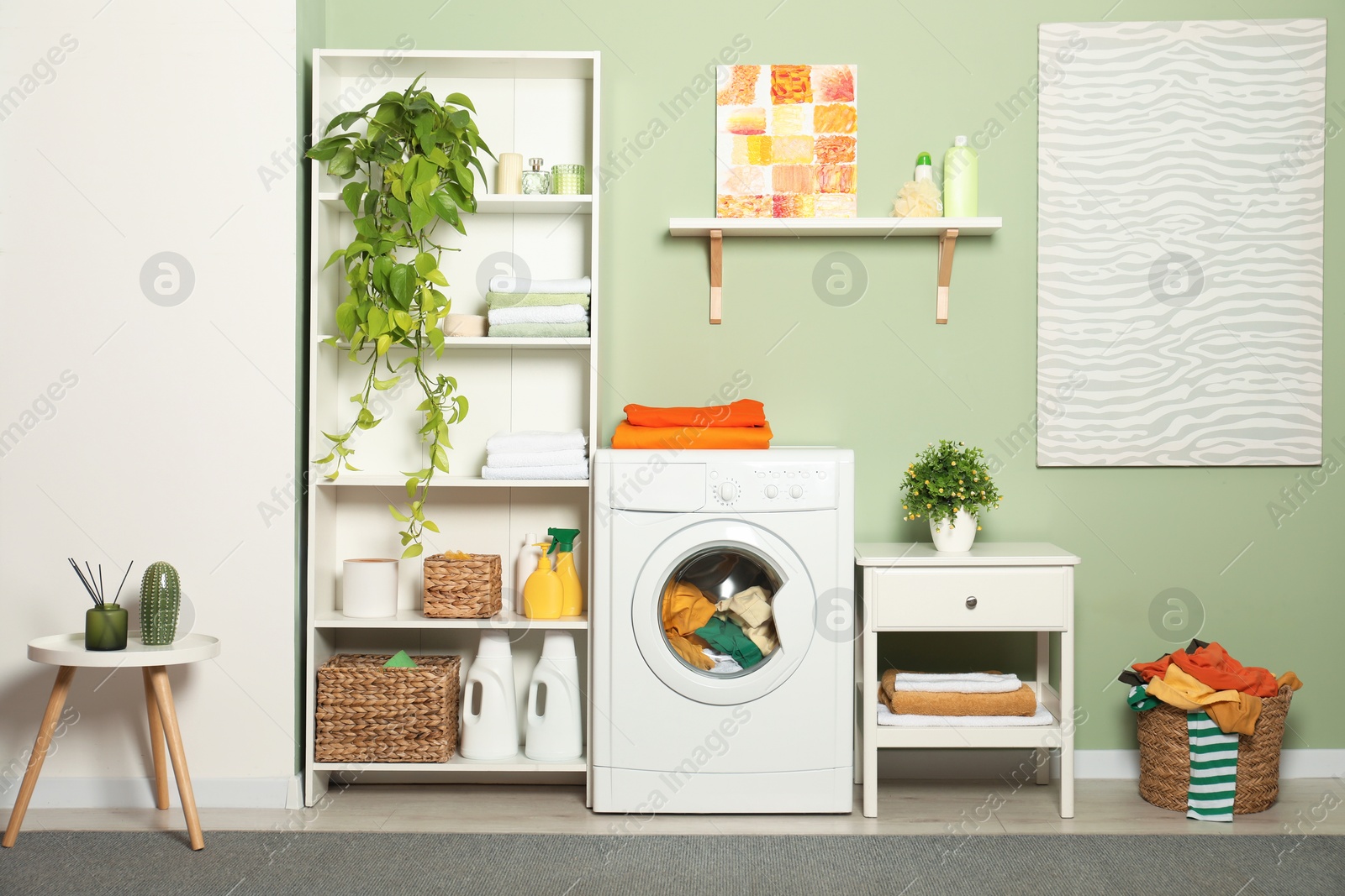 Photo of Washing machine, detergents and basket with laundry in room