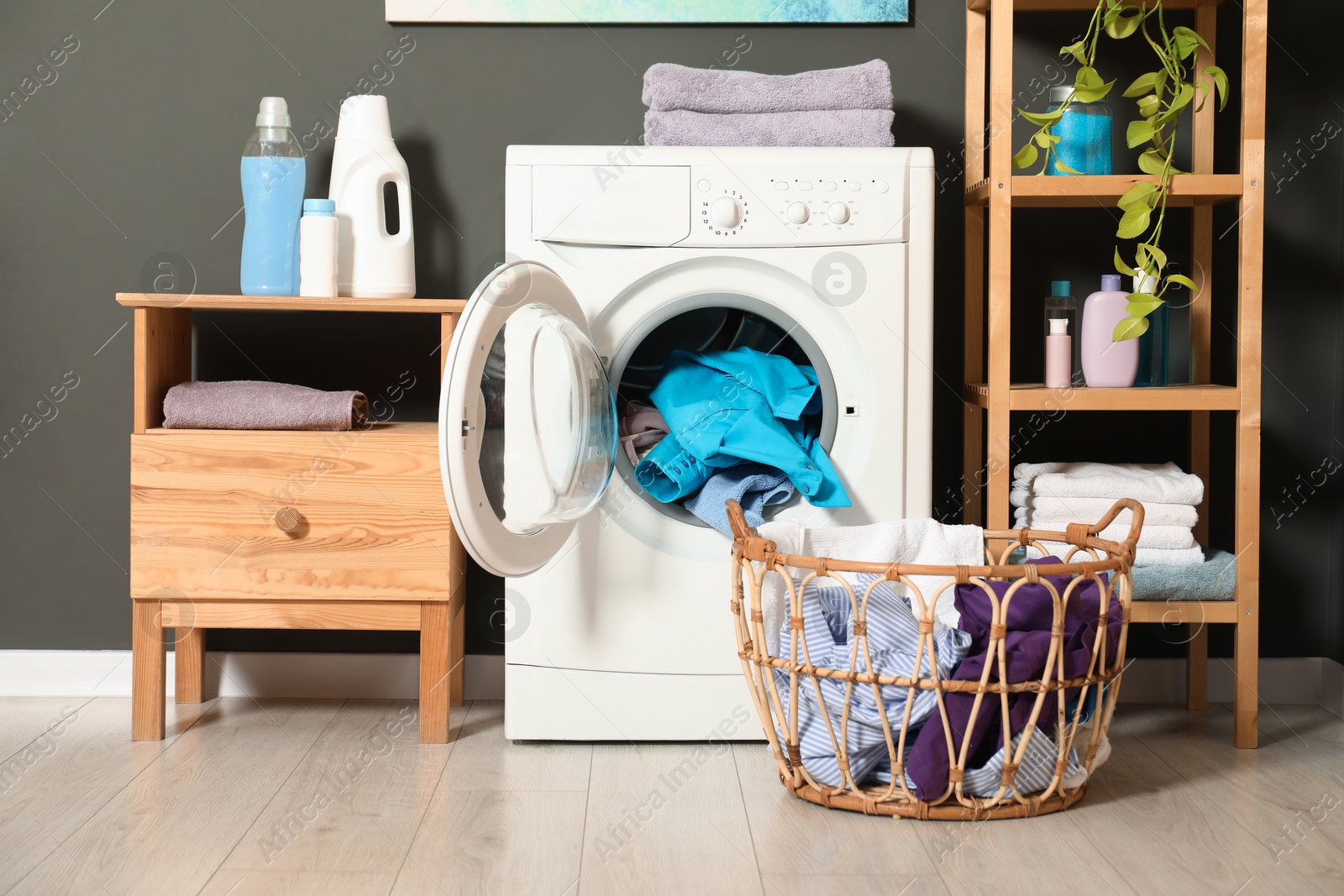 Photo of Washing machine, detergents and basket with laundry in room