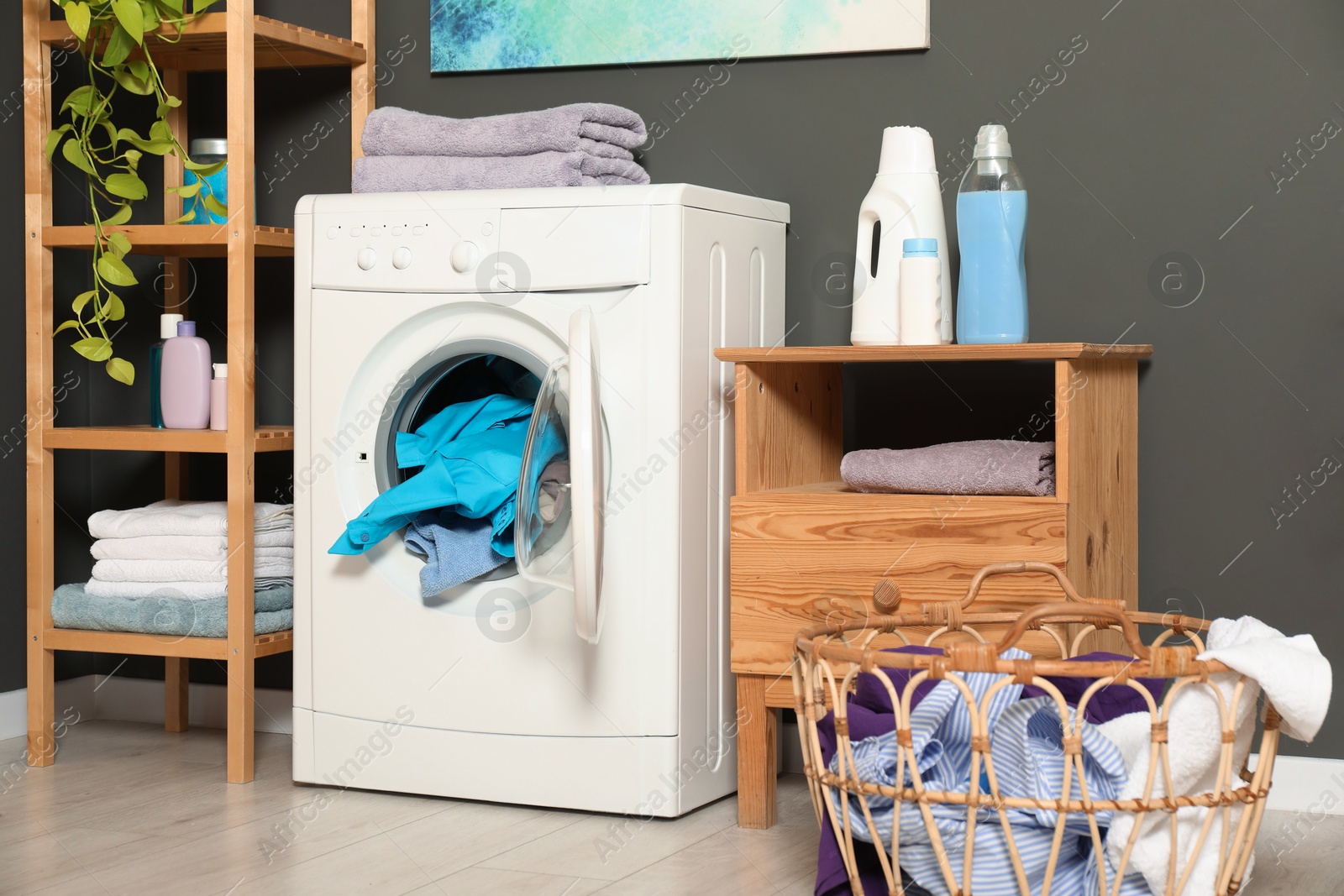 Photo of Washing machine, detergents and basket with laundry in room