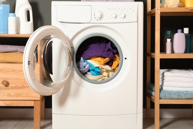 Photo of Washing machine, detergents and towels indoors, closeup