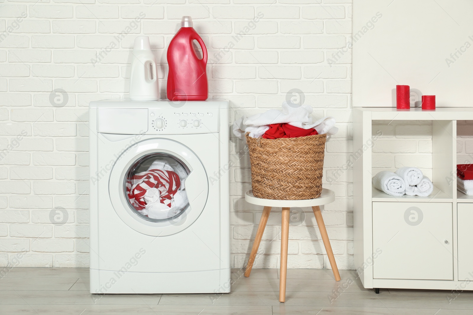 Photo of Washing machine, detergents and basket with laundry in room