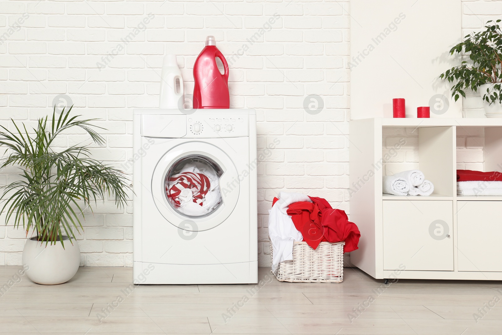 Photo of Washing machine, detergents and basket with laundry in room