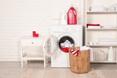 Photo of Washing machine, detergents and basket with laundry in room