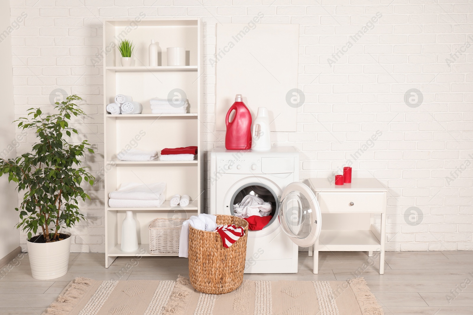 Photo of Washing machine, detergents and basket with laundry in room