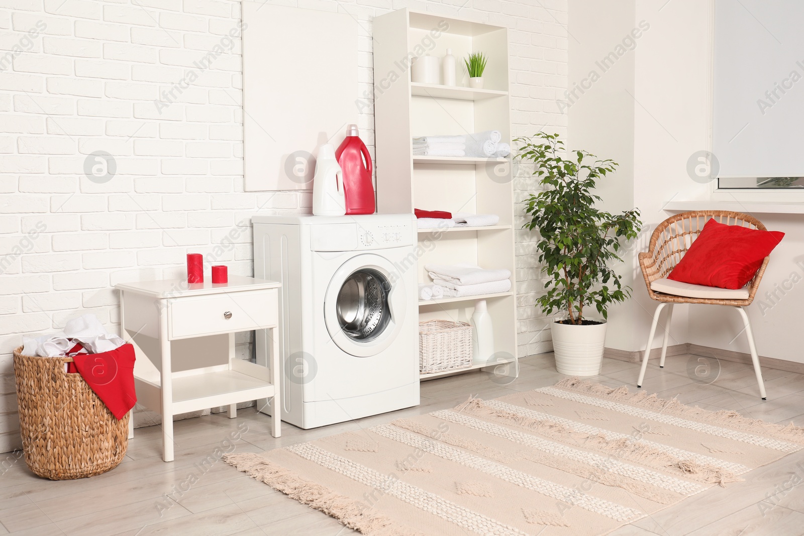 Photo of Washing machine, detergents and basket with laundry in room