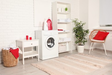 Photo of Washing machine, detergents and basket with laundry in room