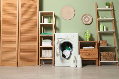 Photo of Washing machine, detergents and towels in room